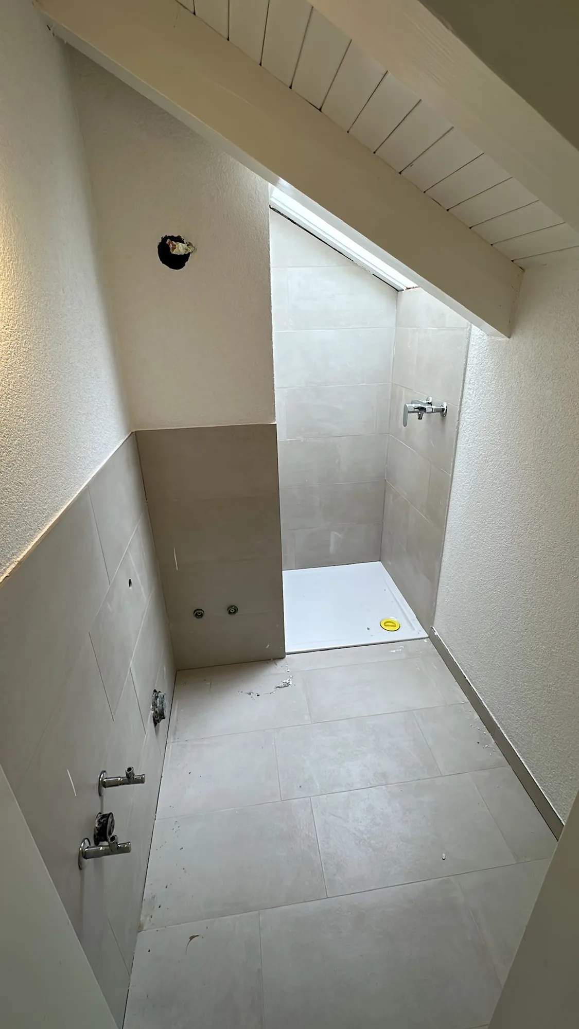Frisch verlegte Plattenbeläge in Duschbereich und Badezimmer
