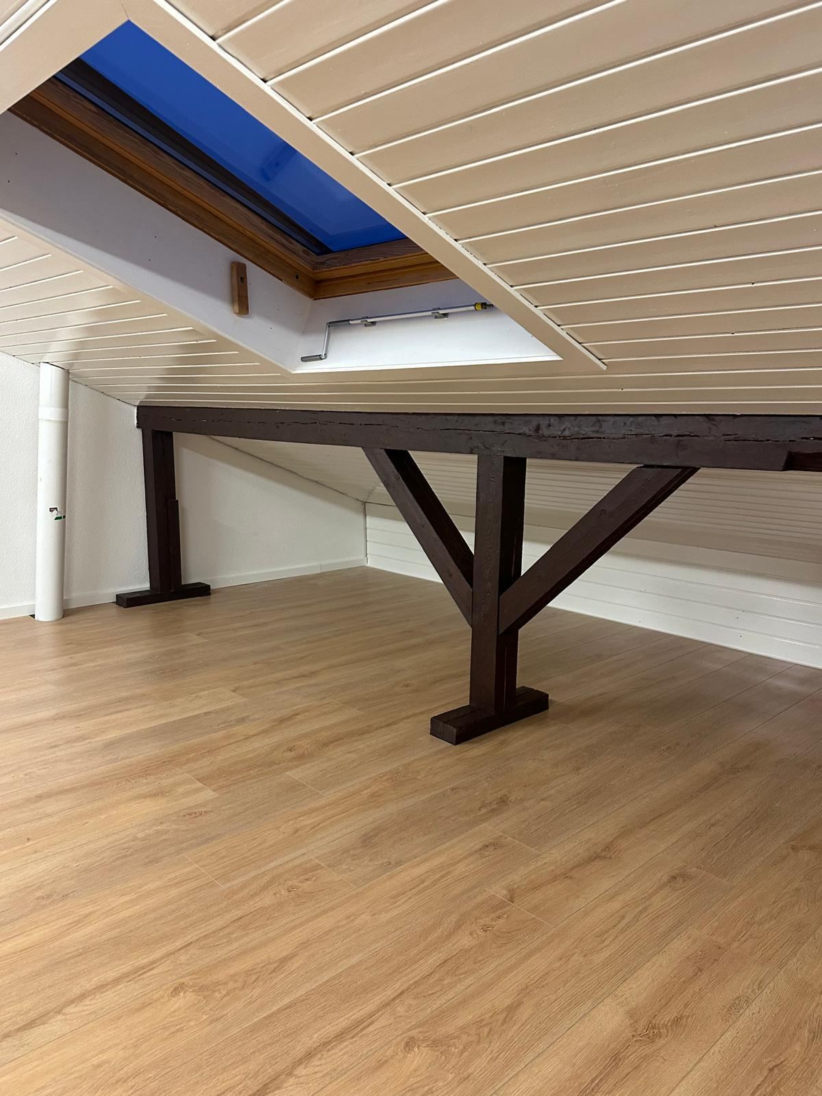 Dachzimmer mit Holzbalken und Dachfenstern